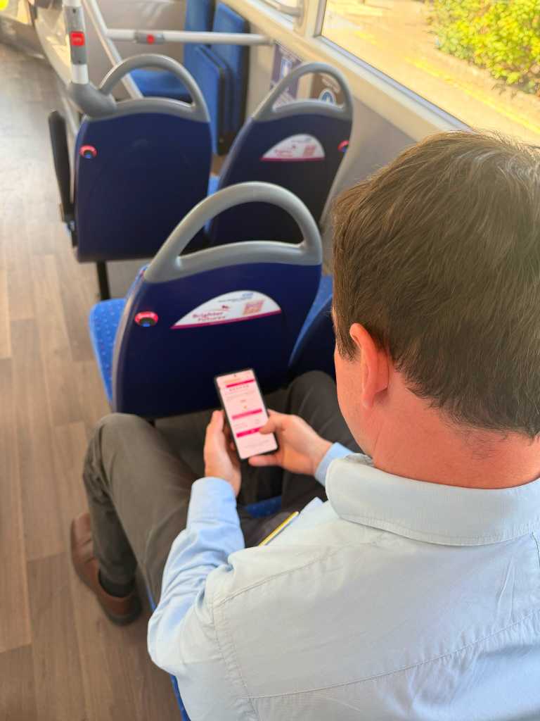 Brighter Futures charity bus with QR code and man using phone